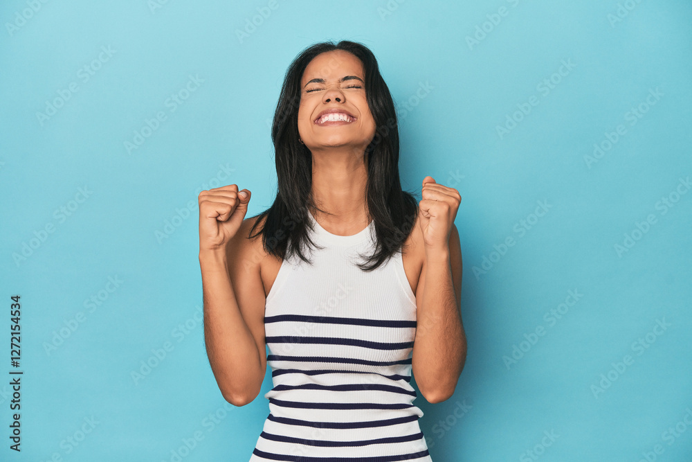 Fototapeta premium Filipina young woman on blue studio celebrating a victory, passion and enthusiasm, happy expression.