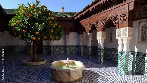Tranquil courtyard with orange tree and fountain in sunlight