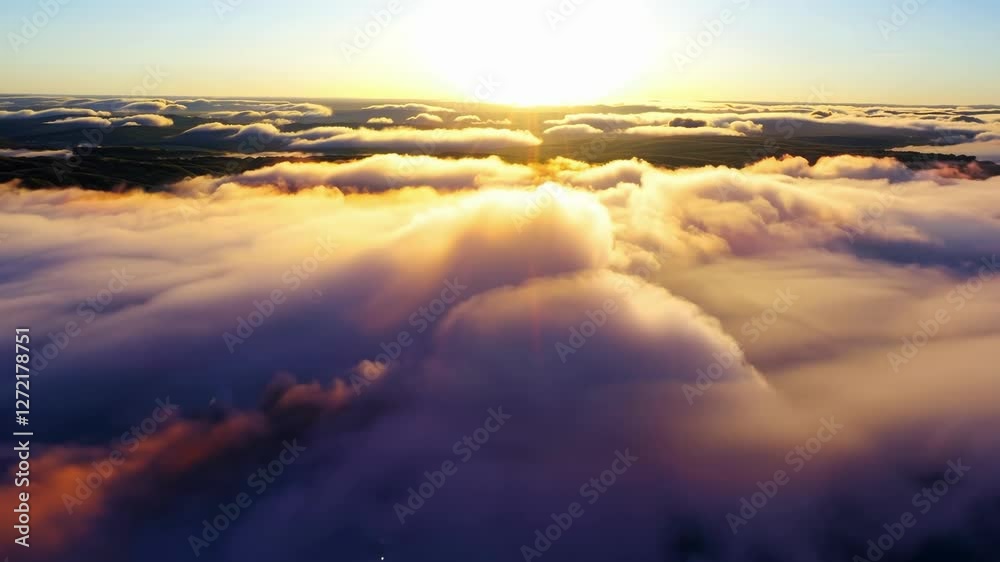 A breathtaking sunrise emerges above a thick layer of clouds in the early morning, casting warm golden hues over the landscape below. This stunning display showcases the tranquility of nature.