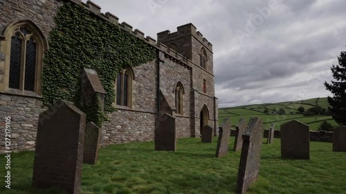 Stone church with gravestones surrounded by lush green hills