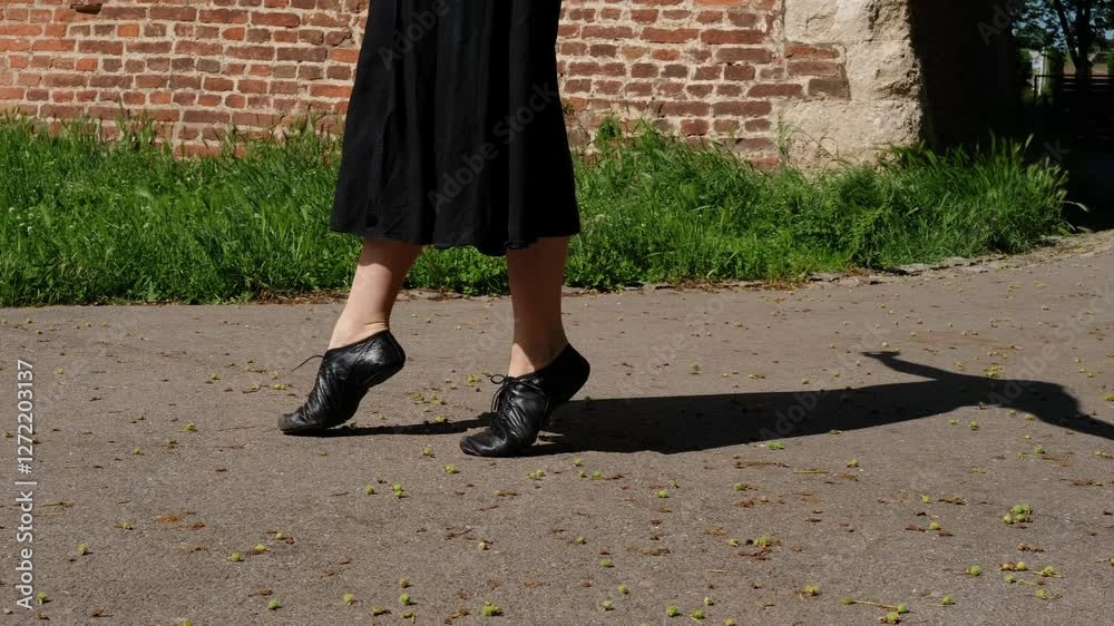 Woman is dancing outside in a summer park. Close view of legs. Female dancer in a black dress makes graceful movements outdoor. 4k horizontal slow motion footage Woman is dancing outside in a summer park. Close view of legs. Female dancer in a black dress makes graceful movements outdoor. 4k horizontal slow motion footage