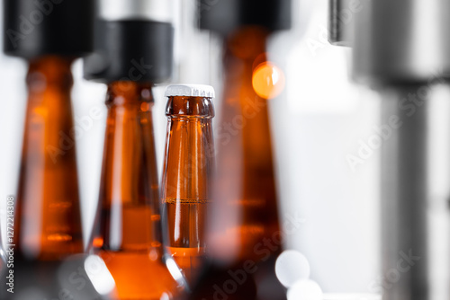 Beer bottling process in modern brewery: close-up of amber bottles on production line