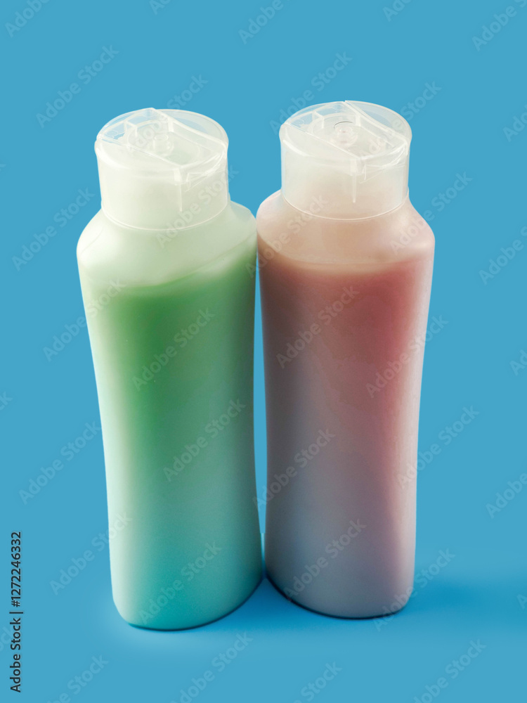 Two plastic bottles or containers with red and green color liquid soap. Ocean blue background. Health and beauty product. Skin and body care. Cosmetic industry.