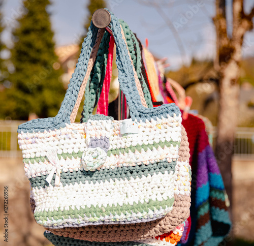 Colorful handcrafted crochet bags hanging outdoors in sunlight