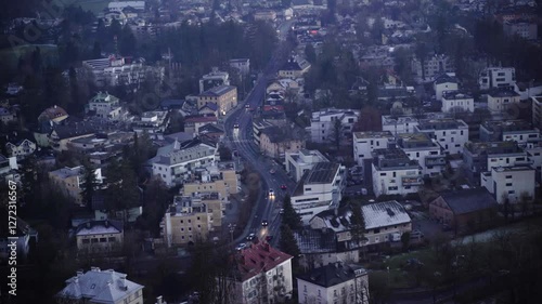 An aerial view of a European town at dusk, featuring winding roads, residential buildings, and city lights in a cold winter setting. 4K 
