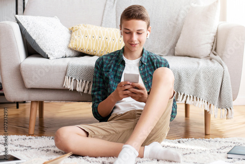 Time for break. Smiling teenager watching video content on smartphone while studying at home