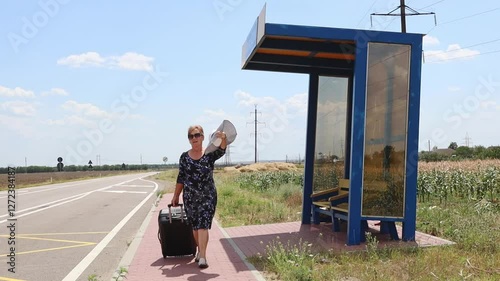 An older woman with a suitcase is returning home from a bus stop.
