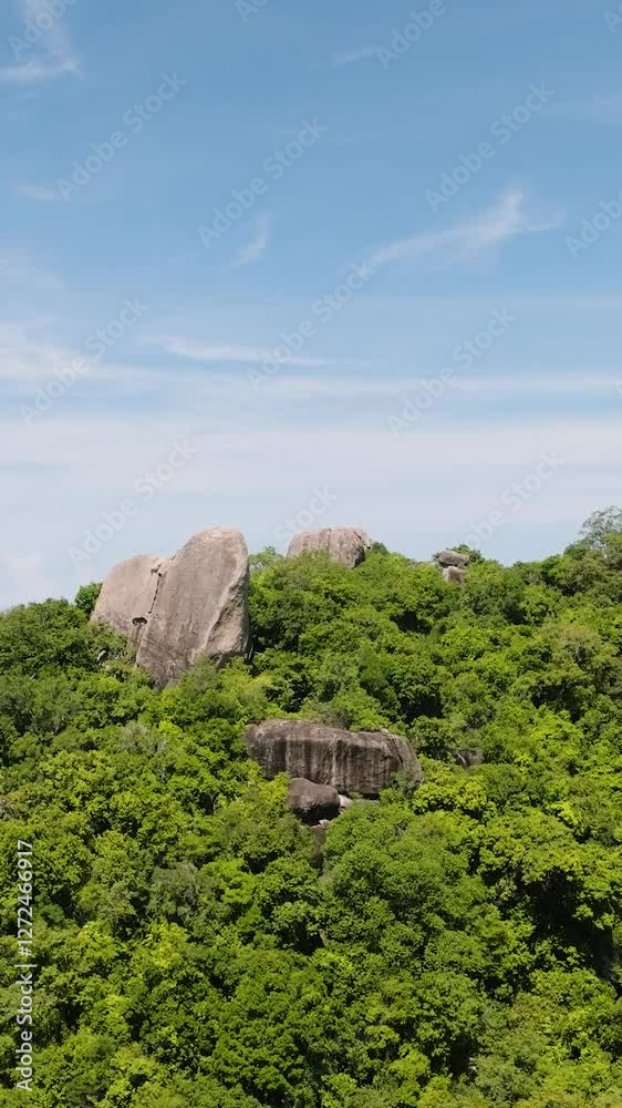 Lush green forested hill with scattered boulders under a clear blue sky. Koh Tao, Thailand. Lush green forested hill with scattered boulders under a clear blue sky. Koh Tao, Thailand.