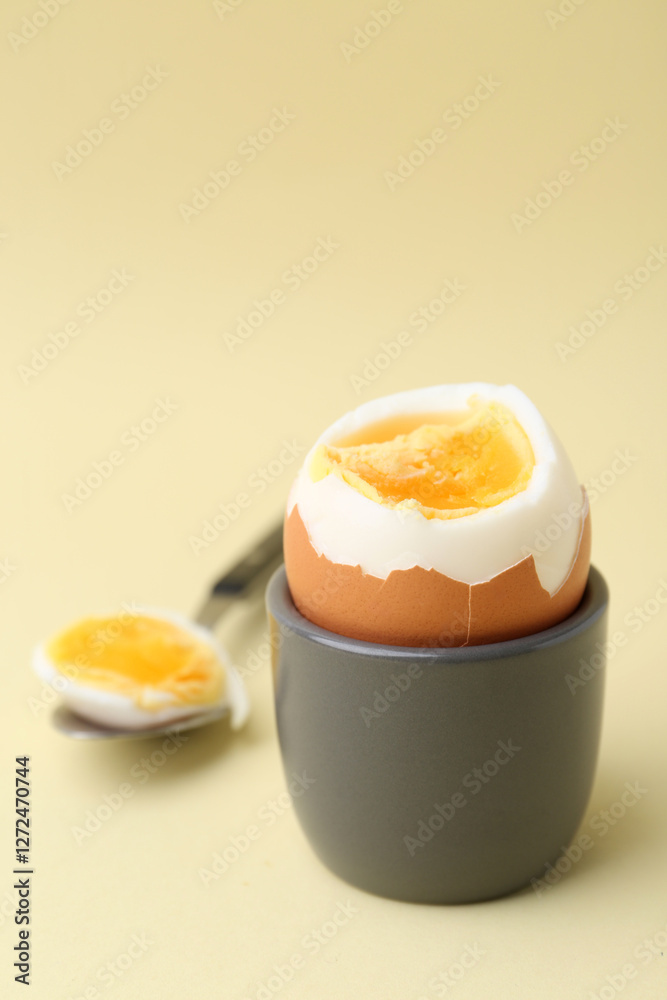 Soft boiled egg in eggcup and spoon on beige background, closeup Soft boiled egg in eggcup and spoon on beige background, closeup