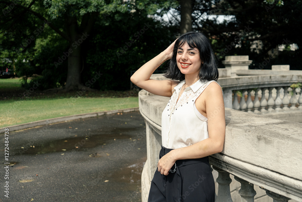 Elegant latin woman posing in a park by a balustrade Elegant latin woman posing in a park by a balustrade