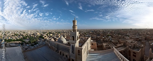Minaret and dome rise above a sprawling cityscape under a blue sky photo
