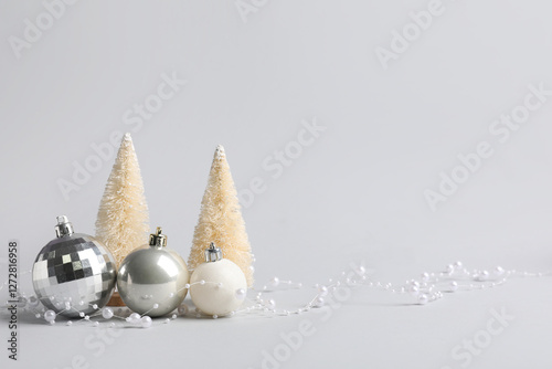 Photos Silver baubles with beads garland and mini Christmas trees on grey background