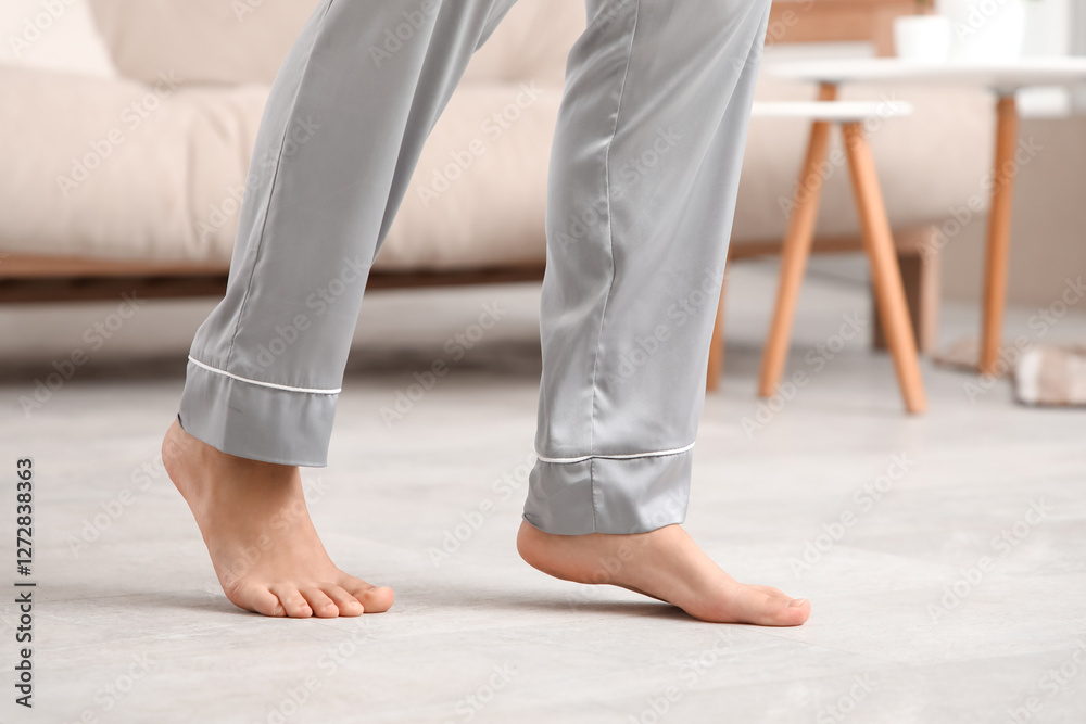 Barefoot female legs in pajamas on floor with heating at home Barefoot female legs in pajamas on floor with heating at home