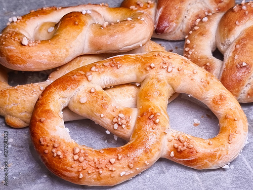 Freshly made salty pretzels at closeup on waxed paper over baking tray