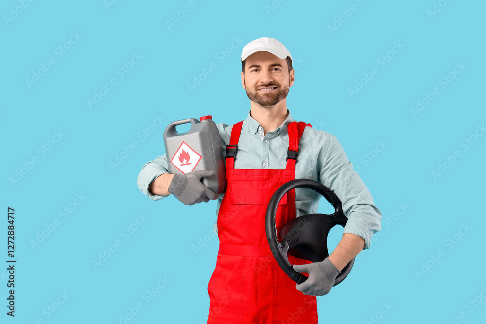 Male mechanic with canister and steering wheel on blue background
