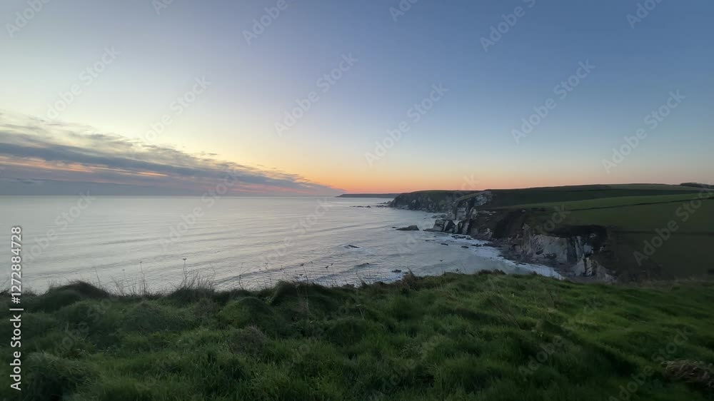 Scenic view of sea from mountain landscape at sunset, with vibrant colors illuminating the horizon and calm water reflecting the fading light of the day. Scenic view of sea from mountain landscape at sunset, with vibrant colors illuminating the horizon and calm water reflecting the fading light of the day.
