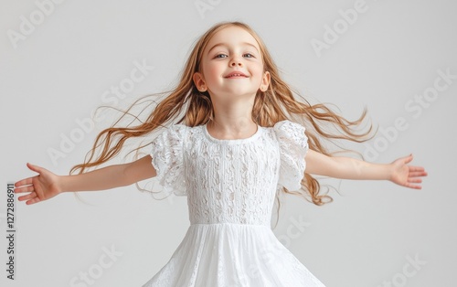 Young girl in white dress joyfully spinning with arms outstretched in bright studio