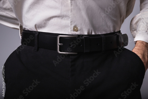 Close-up of man in white shirt and black classic trousers with black leather belt