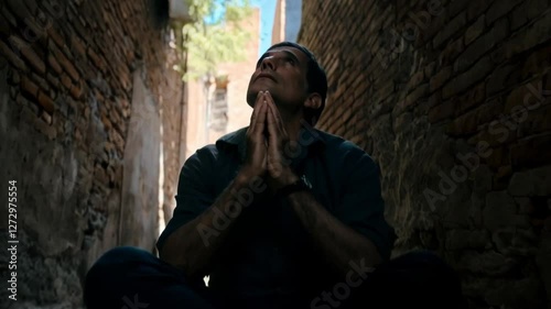 Man praying with hands clasped in the street and looking at the sky