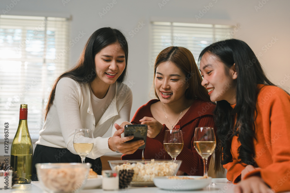 Three young women gather around a table, sharing laughter and engaging with social media on a smartphone. Wine glasses and snacks create a cozy, friendly atmosphere Three young women gather around a table, sharing laughter and engaging with social media on a smartphone. Wine glasses and snacks create a cozy, friendly atmosphere