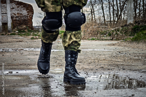 special forces soldier with an automatic rifle wearing a helmet mask and body armor stands against the background of destroyed buildings. The concept of the army and military exercises.