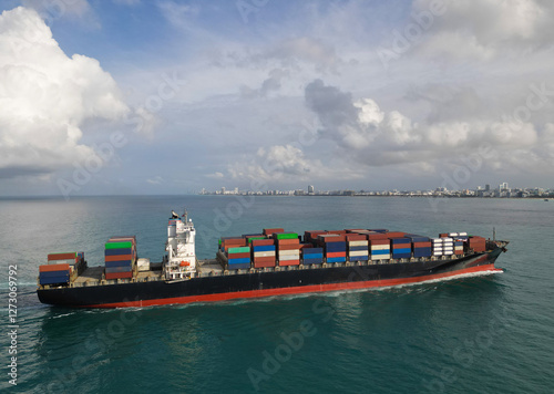 Freight container loaded on cargo vessel. Aerial view cargo ship entering harbor. Cargo business. Container ship. Shipping logistics. Shipping port operations. Cargo ship in sea, aerial view