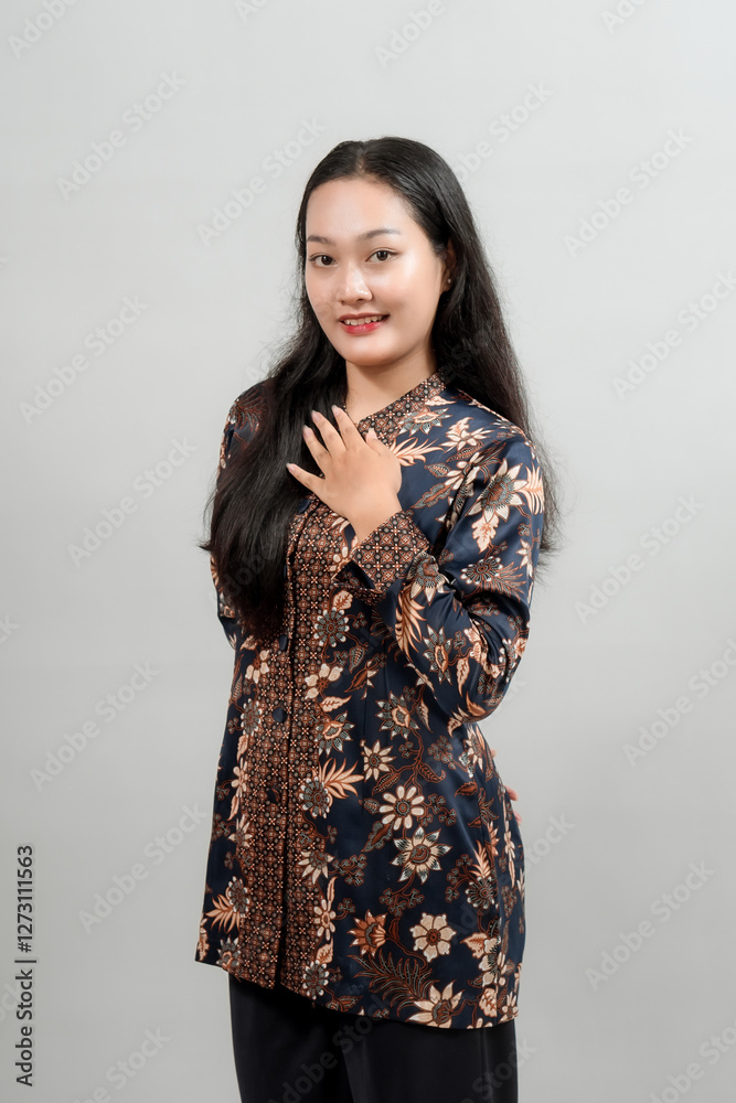 A charming young woman in a stylish Indonesian batik outfit, smiling warmly while placing her hand on her chest, showcasing the beauty and elegance of traditional fashion. A charming young woman in a stylish Indonesian batik outfit, smiling warmly while placing her hand on her chest, showcasing the beauty and elegance of traditional fashion.