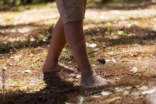 A boy is walking barefoot on the ground in a pine forest. Nature tourism concept. photo