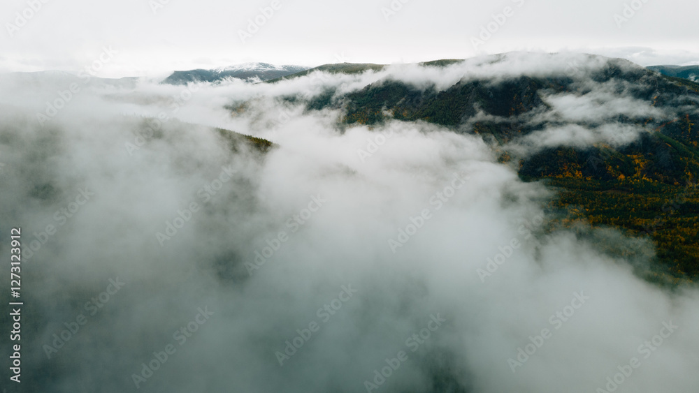 Autumn mountains shrouded in mist, creating a mystical and serene landscape captured in breathtaking aerial drone footage Autumn mountains shrouded in mist, creating a mystical and serene landscape captured in breathtaking aerial drone footage