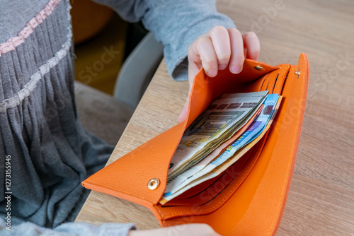 Child opening wallet full euro banknotes money on wooden table, finances, savings, and early financial awareness, Childhood curiosity, money management