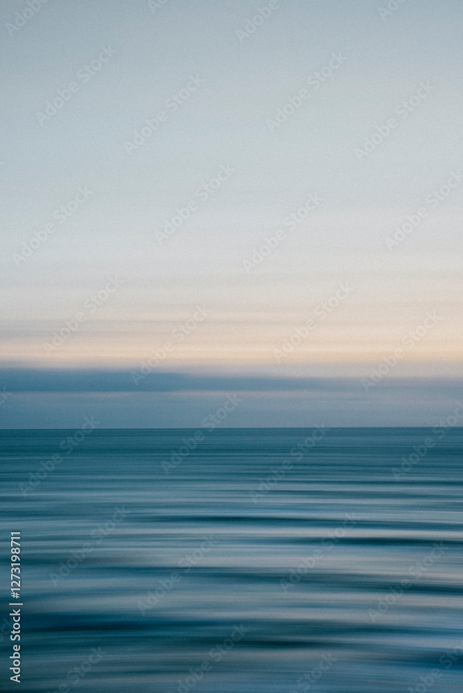 A tranquil ocean scene with a clear blue sky in the background. The water appears calm and still, with no visible waves or ripples. The sky is a light blue color A tranquil ocean scene with a clear blue sky in the background. The water appears calm and still, with no visible waves or ripples. The sky is a light blue color