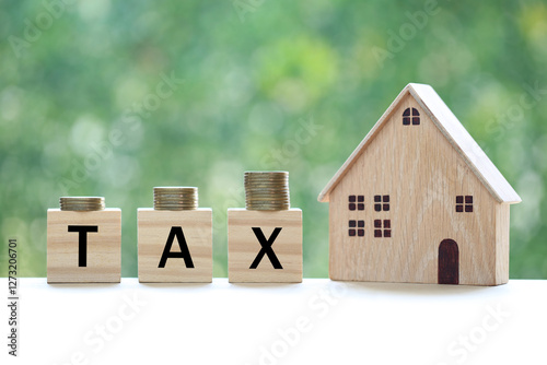 Tax concept,Model house with stack of coins money and tax word on green background,Business investment and Property tax concept