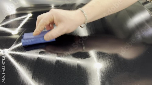 Automotive ceramics. Car service worker applying nano coating on a car detail. Specialistic ceramic coating liquid powder on to sponge by unrecognizable professional. Car detailing process.