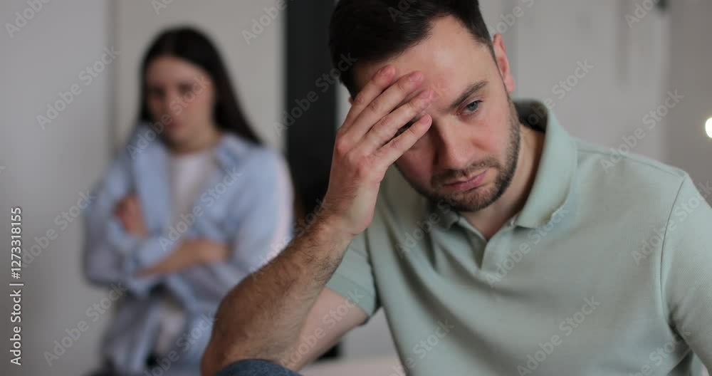 Couple sitting on the bed in bedroom and arguing over a disagreement, the woman is yelling at man, man is experiencing psychological violence from his wife. Disappointment in marriage life lead to Couple sitting on the bed in bedroom and arguing over a disagreement, the woman is yelling at man, man is experiencing psychological violence from his wife. Disappointment in marriage life lead to