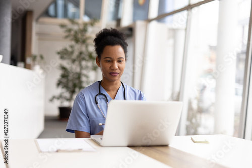 Focused African American nurse entering medical records on a laptop