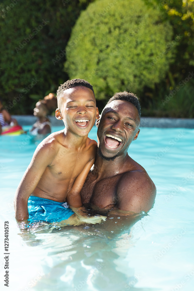 African American father and son are laughing in pool at home African American father and son are laughing in pool at home