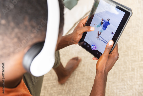 Using tablet and wearing headphones, man editing photo of beach scene photo