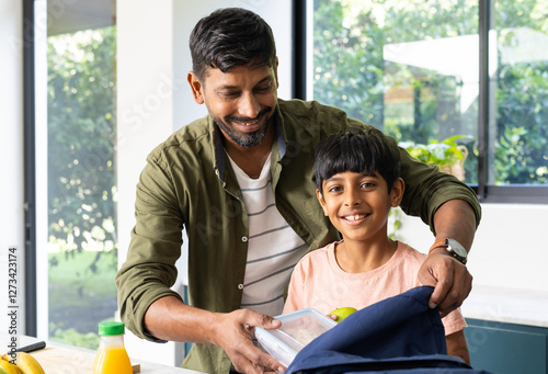 Packing lunchbox, indian father and son smiling in kitchen before school