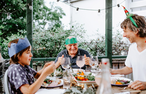 Senior man smiling while giving a thumbs up on the dinner table photo