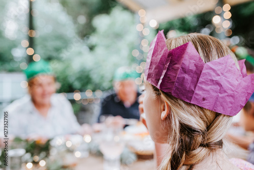 Young teenage girl wearing a paper crown with grandparents on the backdrop. photo