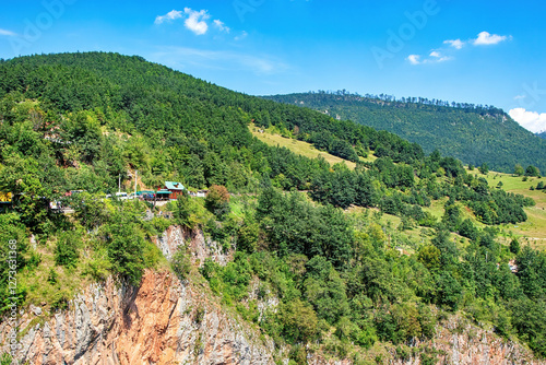 Lush green hills surrounded by vibrant blue skies near a mountain village