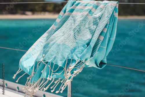 Blue turkish towel blowing on wire railing of boat on the water