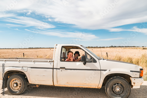 Kids sitting in old farm ute on country road in Australia photo