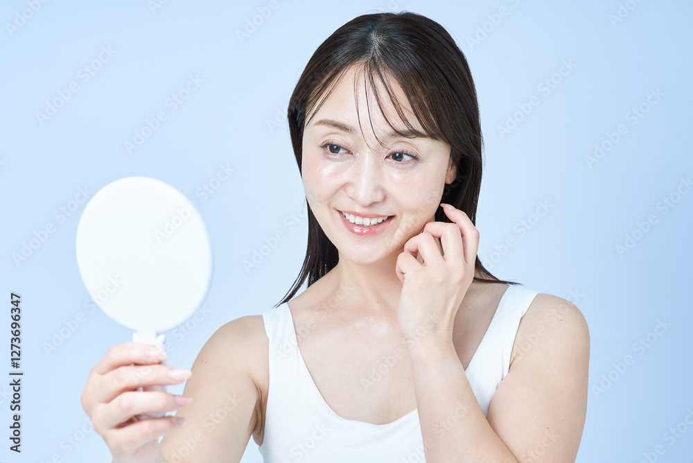 鏡で顔を見るミドル世代の女性