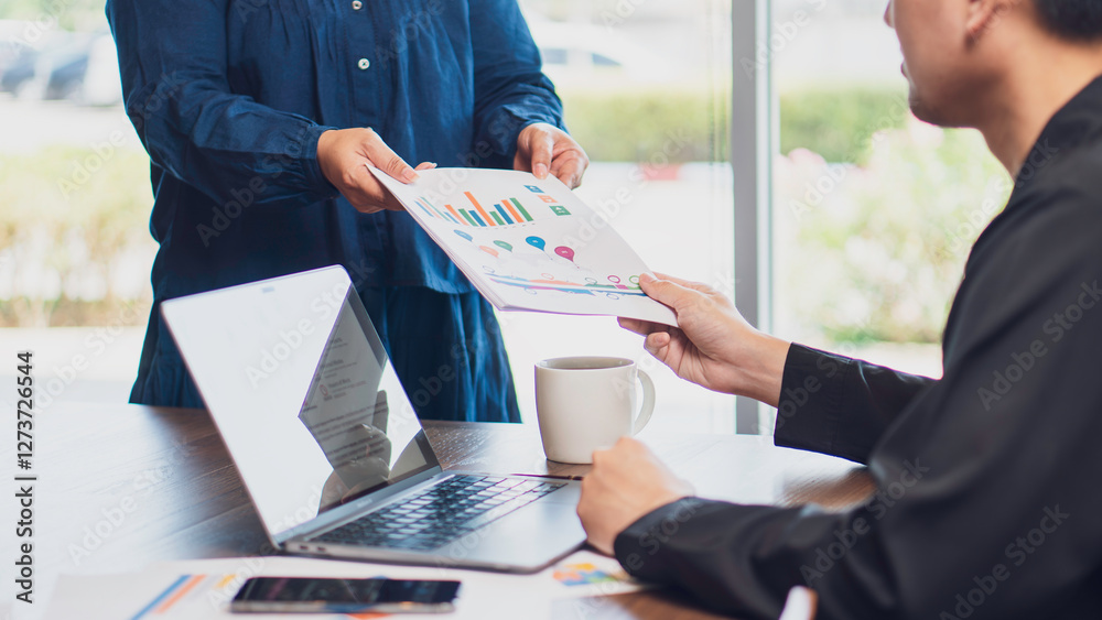 business collaboration, teamwork, and data analysis, featuring handing over a financial report with charts and graphs to a colleague in an office. business strategy, financial planning professional