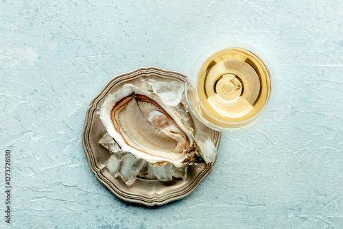 Fresh raw oyster with a glass of wine, on ice, on a slate background, overhead flat lay shot photo