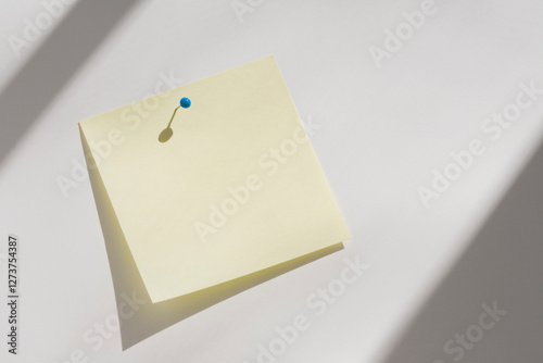 Blank yellow adhesive note pinned to white board