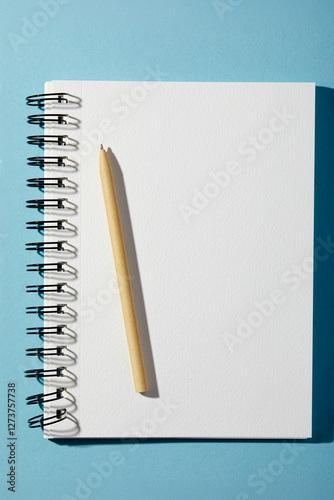 Spiral notebook and pen on blue background