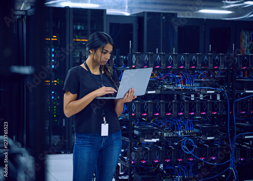 Female technician using laptop in server room 