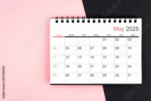 May 2025 desk calendar on pink and black background, Flat lay.